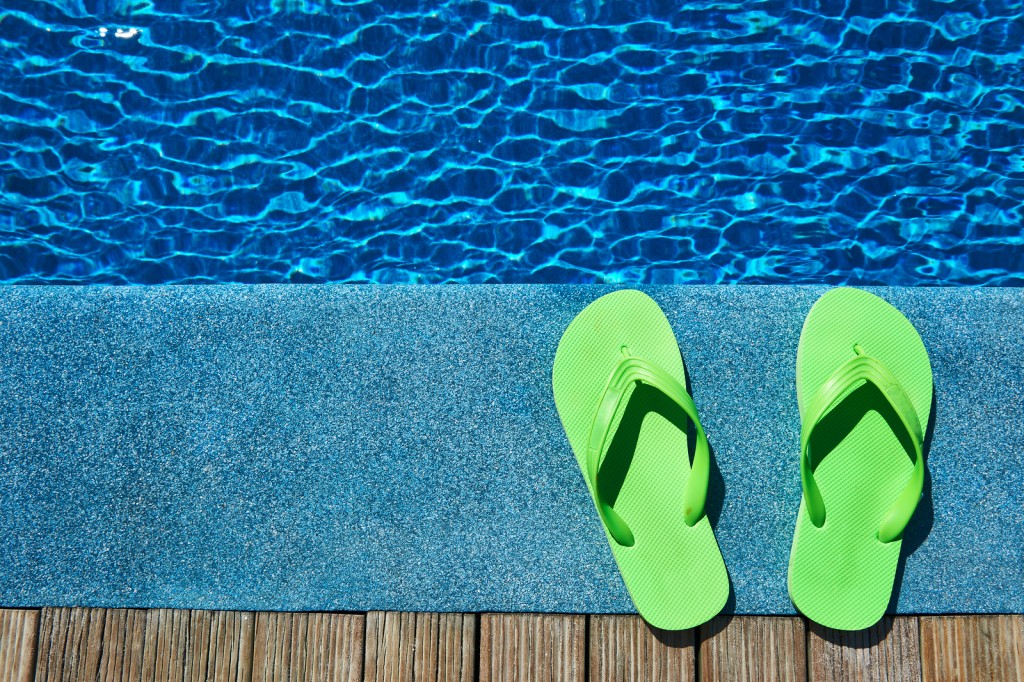 Green slippers by a swimming pool