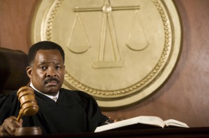 African American judge holding mallet in courtroom